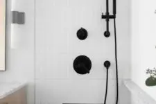 04 a chic bathroom with white skinny tiles, a niche shelf with black edge for storage, black fixtures