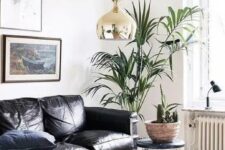 04 a gorgeous contemporary living room with a black leather sofa, stacks of books, potted plants and a chic gallery wall