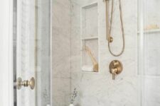 07 a chic shower space done with marble tiles, niches used for storage, brass fixtures and a wooden stool