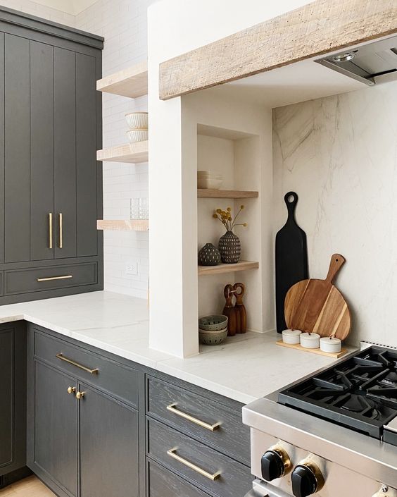 A modern farmhouse kitchen with graphite grey cabinets, built in ones, a niche with small shelves that are used fro storage and display