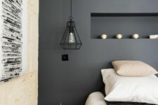 08 a modern bedroom with a soot accent wall and a niche with decor, a bed with neutral bedding, black pendant lamps