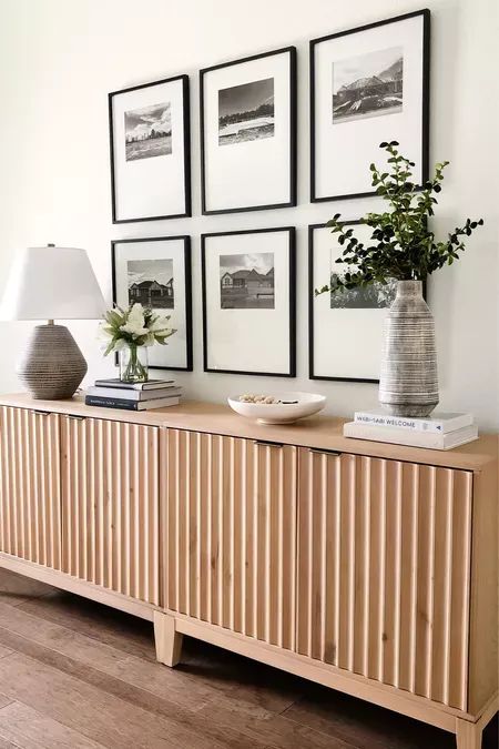 a chic Scandinavian interior with a fluted console, a grid gallery wall, a table lamp, some decor and some books