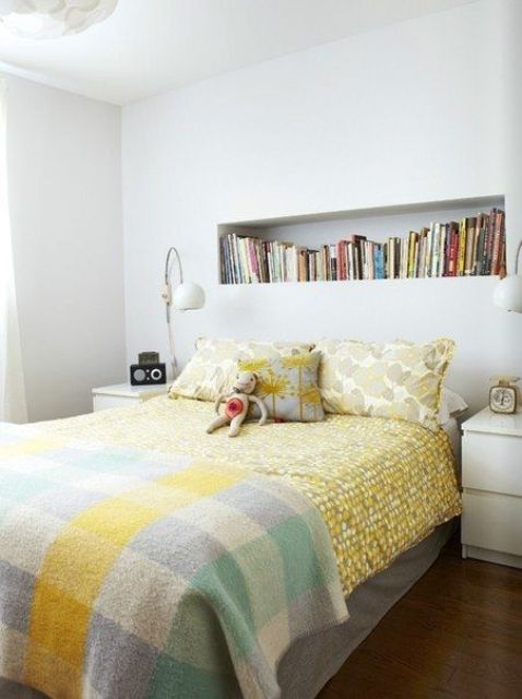 a modern neutral bedroom with a bed with bright bedding, a long headboard niche as a bookshelf, white nightstands and lamps