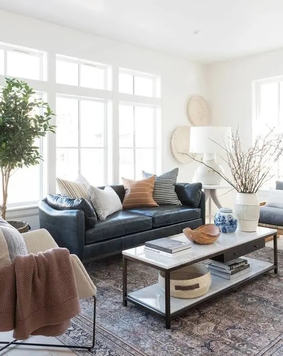 a stylish modern and boho living room with a navy leather couch accessorized with various pillows