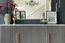 11 a chic sideboard with grey reeded doors, gold handles and legs, a refined mirror, some decor and candles for a lovely entryway