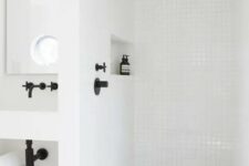 12 a contemporary white bathroom clad with square tiles and black fixtures, a niche shelf, a wall-mounted vanity is stylish