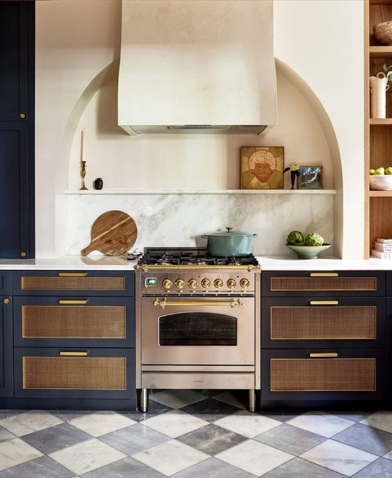 a refined and chic kitchen with navy cabinets, cane inserts, an arched niche with a shelf with some lovely decor - this nice is a decorative element