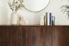 14 a dark-stained sideboard with beautiful decor, vases, books and a round mirror over it is a stylish and catchy idea