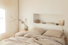 14 a serene Scandinavian bedroom with a timber wardrobe, a bed wiht neutral bedding and a headboard niche used for decorating the space