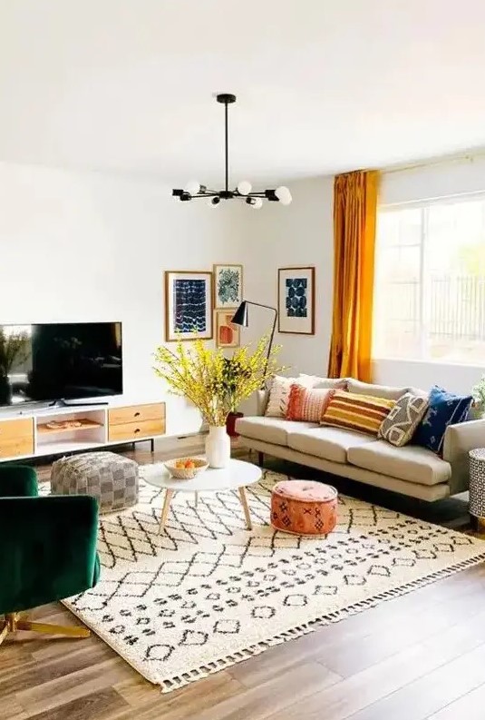 A bright mid century modern living room with a comfy sofa, a green chair, a TV unit, printed textiles and a bright gallery wall