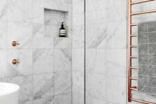 18 a marble tile bathroom with a dark floor, a tub, a shower and copper hardware for a chic and bold look