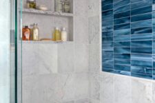 21 a modern bathroom clad with grey and blue marble tiles, a niche with shelves used for storing things, a built-in bench