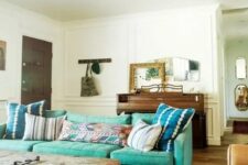 21 an eclectic living room with a mid-century modern turquoise sofa, a rough wooden table, a chair, a wooden dresser and some mirrors on it