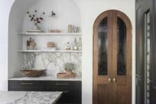 23 a contemporary kitchen with a large arched niche with built-in dark cabinets, open shelves and a marble backsplash is adorable