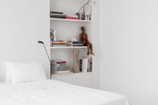 28 a Scandinavian bedroom with a bed and neutral bedding, a niche with shelves used for storing books and various decor is a lovely space
