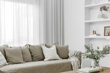 28 a neutral living room with a grey linen sofa and pillows, a stained table, a niche with shelves, a jute pouf and greenery