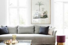 29 a chic living room with a grey linen sofa and pillows, a mauve pouf, a tiered coffee table and a bold artwork