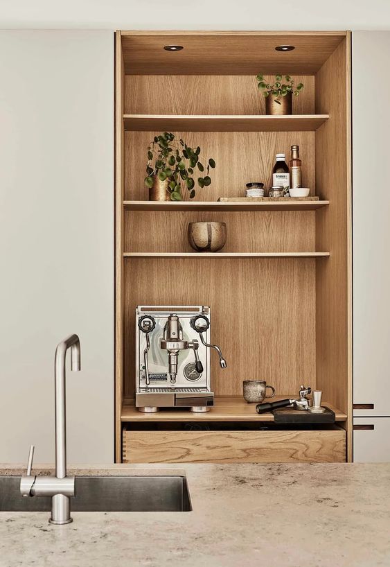 A niche with a built in cabinet with drawers, with open shelves that are used for storing and displaying things