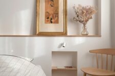 32 a welcoming neutral bedroom with a bed and neutral bedding, a niche with shelves, some art and a stained chair