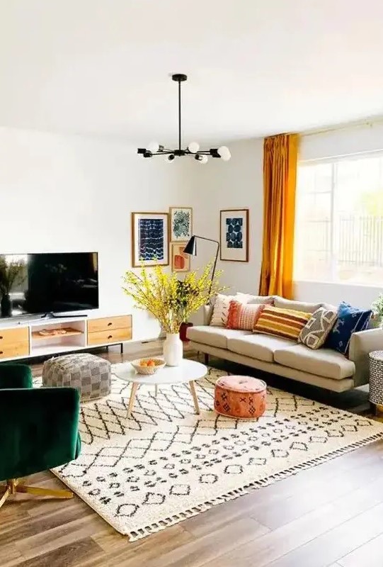 A bright mid century modern living room with a comfy sofa, a green chair, a TV unit, printed textiles and a bright gallery wall
