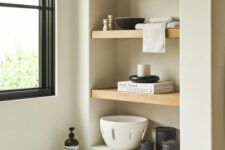 33 a neutral bathroom with a niche with wooden shelves used for placing decor there to make the bathroom look cooler