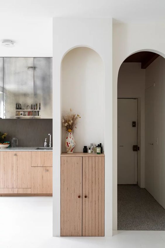 A tall and narrow arched niche with a small cabinet built in and some decor is a lovely idea to use that awkward nook you might have in your space