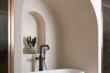 34 a neutral bathroom with an oval tub placed in a niche, with an additional niche with a potted plant looks jaw-dropping
