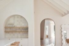 34 an airy neutral kitchen with a dining space, with an arched niche clad with neutral tiles, wooden shelves and a built-in sideboard is amazing