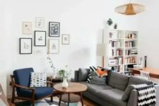 36 a mid-century modern living room with a bold printed rug, a grey sofa, a navy chair and a white stool, a cool gallery wall