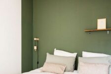 37 a minimal bedroom with a niche painted green, a bed in it, some sconces and a ledge for decorating