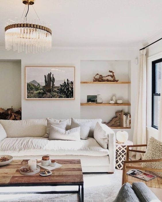 a beautiful neutral living room with built-in shelves with decor, a white cotton sofa, a wooden coffee table and rattan chairs