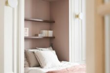 41 a refined French bedroom with a large niche painted dusty pink, a bed placed in there and some stained shelves and sconces