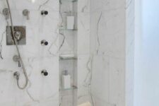 41 a refined shower with marble tiles, with a tall and narrow niche with shelves used for storing various stuff