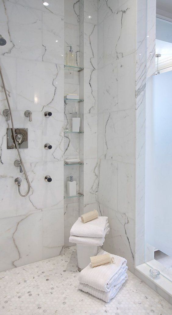 a refined shower with marble tiles, with a tall and narrow niche with shelves used for storing various stuff
