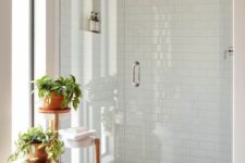 43 a serene white bathroom clad with hexagon and subway tiles, with a niche for storage, a plant stand with potted greenery
