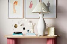 43 an eye-catching console table with pink fluted legs, a lamp with a fluted lampshade, some deco and a gallery wall