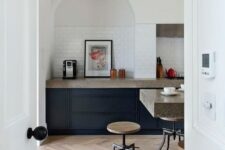 44 a modern kitchen with navy cabinets, grey granite countertops, an arched niche clad with tiles and artwork