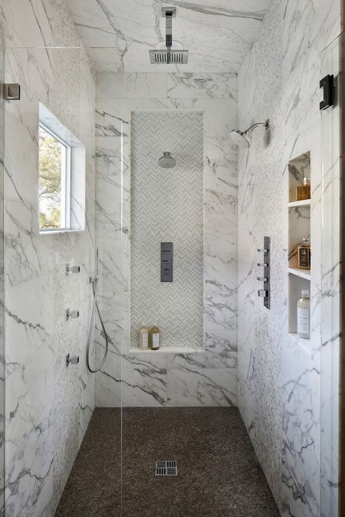 a shower space clad with marble tiles, with niches used for storing things that are necessary for washing, a window for naturla light