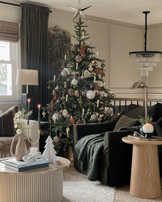 a beautiful living room with a black chair and a white sofa, a fluted coffee table and a round one, a crystal chandelier and a Christmas tree