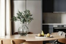 47 a black kitchen, a round table with a fluted base, light-stained chairs, greenery in a vase are a chic and modern combo