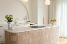 47 a refined and beautiful kitchen with white cabinets, a terracotta tile kitchen island, an arched niche for decor and pendant lamps