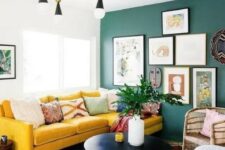 48 a bright boho living room with a green wall and a gallery wall, a yellow velvet sectional, a retro chandelier and a black round table
