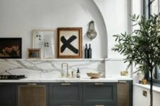 51 a stylish charcoal grey kitchen with a white marble backsplash and countertops, an arched niche with a ledge and a gallery wall in it
