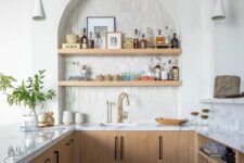 52 a stylish modern kitchen with stained lower cabinets, white stone countertops, an arched niche with open shelves that are used as a home bar