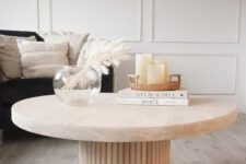 55 a beautiful coffee table with a fluted base and an oval stone tabletop, with decor and books is amazing