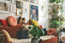 55 a maximalist living room with a colorful gallery wall, a rust-colored velvet vintage sofa, a round table and potted plants