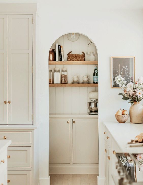 a white modern farmhouse kitchen with an arched niche that houses a pantry with shelves, a cabinet is a lovely idea that saves space
