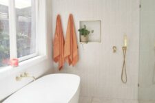 56 an airy modern bathroom with a shower space, an oval tub, a terrazzo floor, a skinny tile wall and a niche for decor