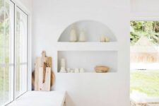 58 an airy white kitchen with an arched niche with beautiful tableware on display is a chic and lovely space