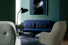 59 a chic and stylish living room with green walls, a navy loveseat, grey chairs, a glass coffee table and a bold and contrasting artwork